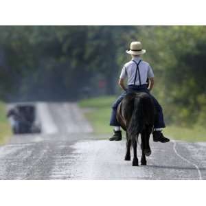  With a Buggy Approaching in the Distance, an Amish Boy 